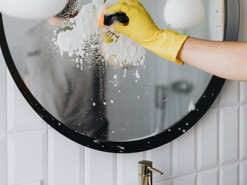 faceless person cleaning mirror in bathroom