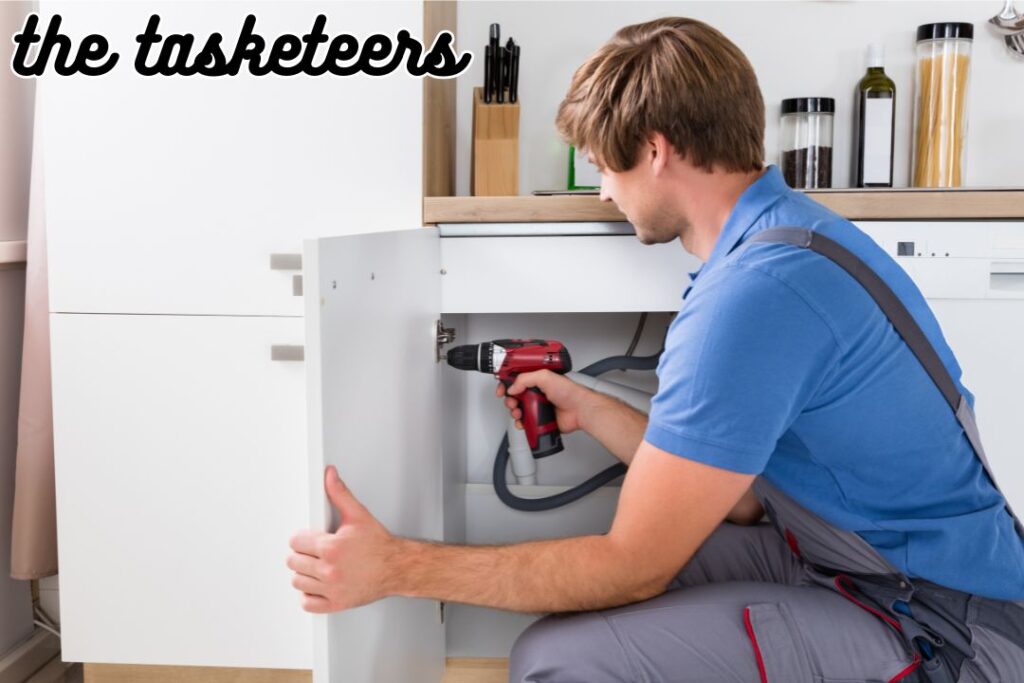 Handyman Fixing a Kitchen Cabinet door by adjusting the hinges.