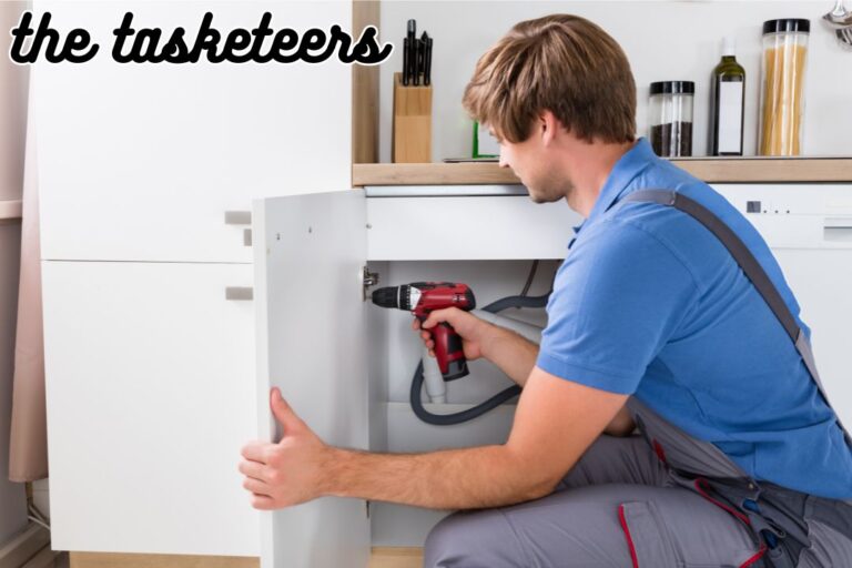 Handyman Fixing a Kitchen Cabinet door by adjusting the hinges.