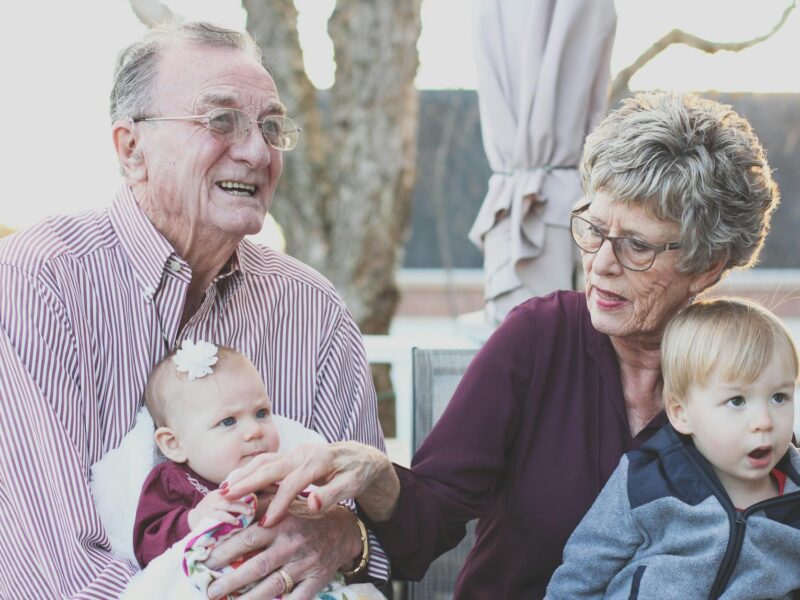 grandmother and grandfather holding child on their lap