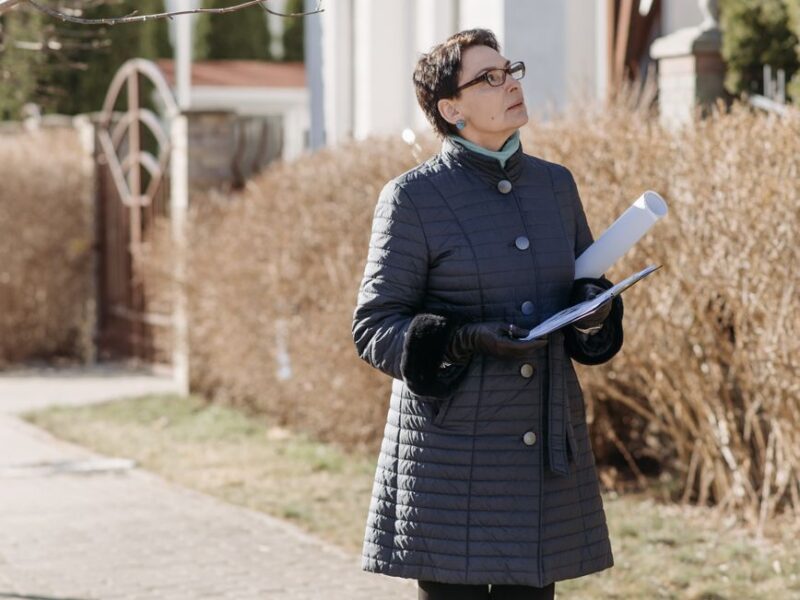 woman in blue coat standing on sidewalk